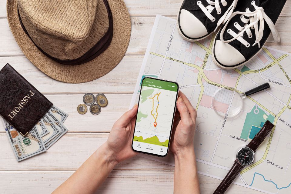 Two hands holding a phone with travel items.